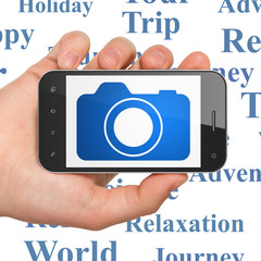 Tourism concept: Hand Holding Smartphone with Photo Camera on display