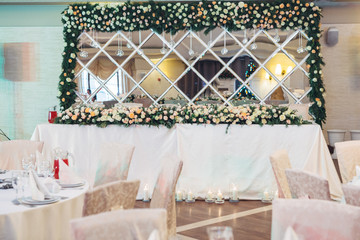 Mirror with garland of roses stands behind long table