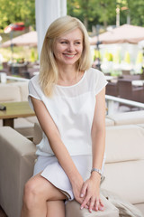 Beautiful blonde woman sits in a summer cafe and rests