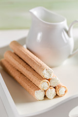 Waffle tube fill with cream on wooden table