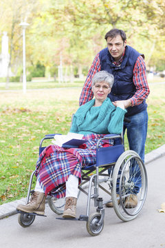  The woman in a wheelchair with her son walking among the park