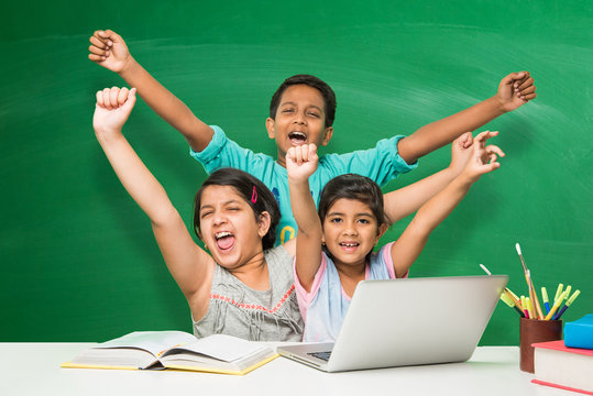 indian school kids using laptop in a classroom over green chalkboard background with doodles