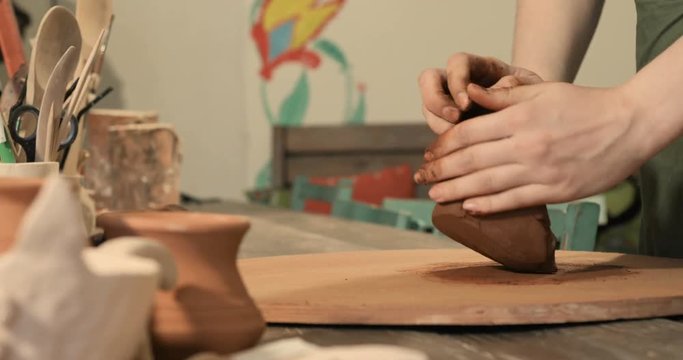 Adult female potter master preparing the clay on table