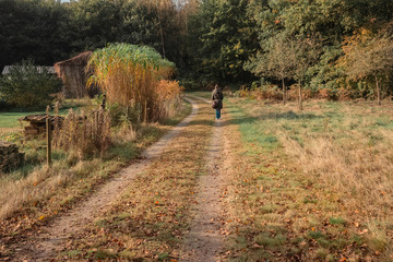 Woman walking over driveway in autumn backyard.