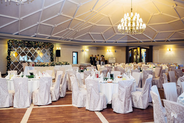 Chairs stand at fancy served dinner tables side by side