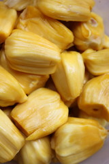 Many yellow jackfruit are in a white plate.