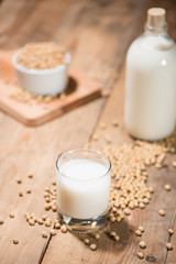 Soy milk or soya milk and soy beans on wooden table.