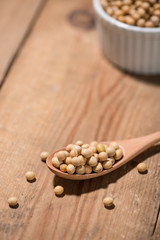 Soya beans in spoon on wooden table.