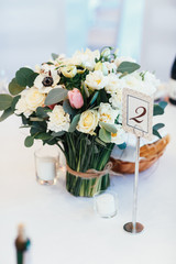Card with number 2 put on a stick stands before vase with bouquet of roses