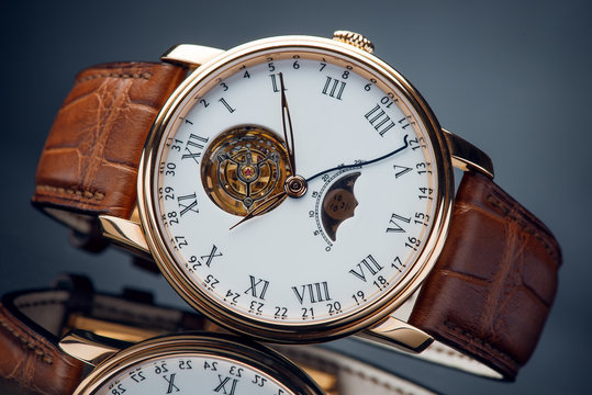 A luxury brown chrome wristwatch with red leather strap