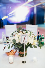 Card with number 1 put on a stick stands before vase with bouquet of roses