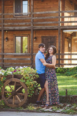 Romantic young couple hugging each other near a decorative wooden carts with flowers, on a background of rustic style.