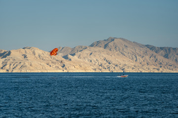 Parasailing above sea during vacation. Leisure activity in touristic journey to the exotic country. Paragliding over the Red sea.