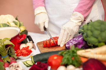 Woman with gloves cutting tomato