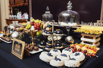 Black plate with blueberries on cakes stands before lettering 'Desert bar'