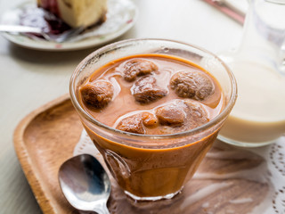 Frozen thai tea in glass with fresh milk and cake on wooden table