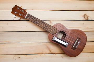 Hawaiian four-stringed ukulele guitar and iron harmonica on wooden background