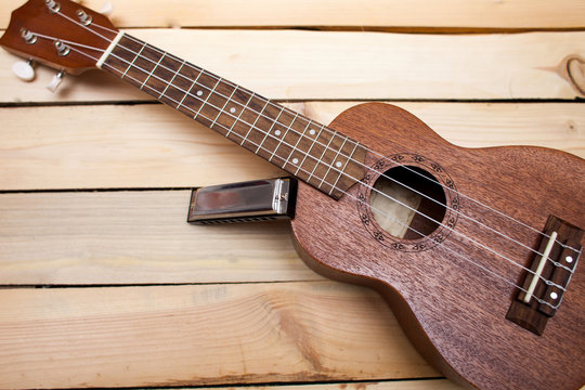 Hawaiian four-stringed ukulele guitar with sliced juicy orange oranges and an iron lip accordion on wooden background