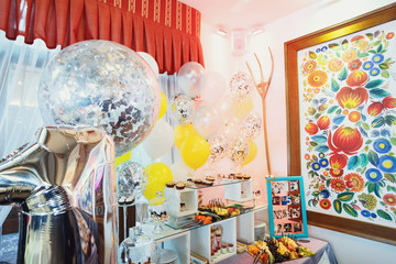Sparkling balls and yellow balloons hang in the room