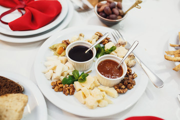Bowls with sauces stand on plate with nuts and cheese