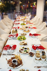 Long dinner table served with white plates and red napkins