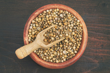 Dried coriander seeds and scoop in wooden bowl. Top view