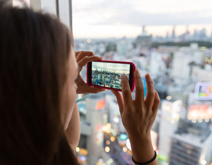 A young woman taking a picture of the city from her hotel room