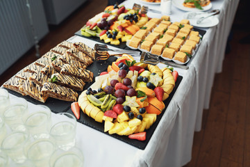 Sliced fruits and pieces of cakes on black dishes