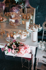 Glass plates with white marshmallows, eclairs and cakes on little white table
