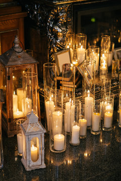 Shiny candles in tall glass vases stand on marble floor