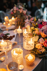 Little candles in glasses stand on dinner table