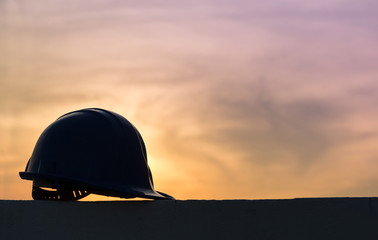 The safety helmet silhouette at construction site with sunset background