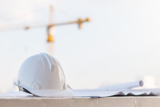 The White Safety Helmet At Construction Site With Crane Background