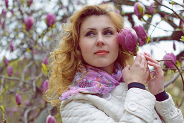 Obraz premium A romantic woman walks in the environment of gentle magnolias in the botanical park breathes a pleasant aroma of flowers