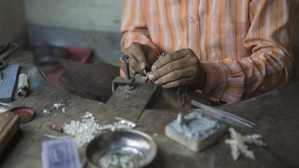 Indian Jeweler making an Oriental Jewelry in workshop. Handmade traditional jewel Manufacturing in Jaipur