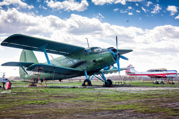 Retro passenger biplane and small sports airplane at the ground airfield