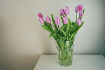 Fresh pink tulip flowers bouquet in a glass jar on white table