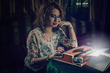 Woman sitting at a typewriter, portrait. Added noise.The focus is on the typewriter. The entire photo is darker, like the act itself and the effect of the transaction on a typewriter, it creates magic