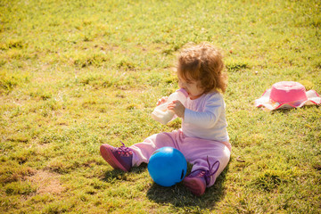 Fototapeta premium Portrait of a baby girl with a bottle in park