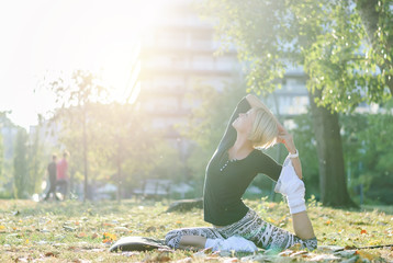 Beautiful young woman with short blond hair, doing yoga in the autumn park