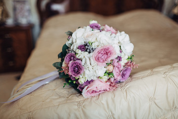 The wedding bouquet for bride stands on the bed