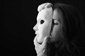 Beautiful brunette girl holding a theatrical mask in white gloves
