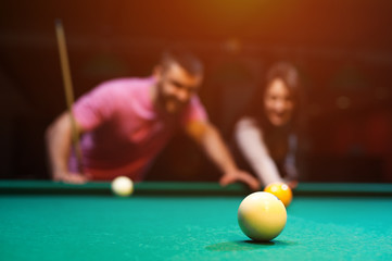 Romantic couple playing billiard in dark club
