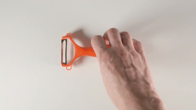 TOP VIEW: Human hands puts a peeler on a white table