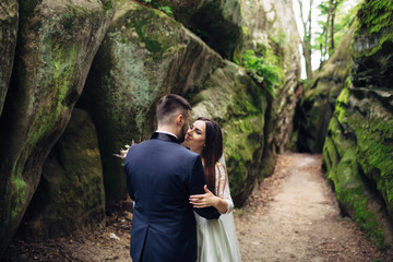 The lovely couple in love embracing near stones
