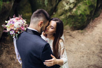 The lovely couple in love embracing near stones