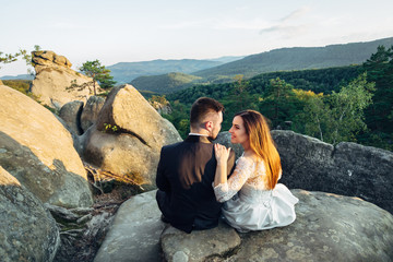 Naklejka premium The lovely couple in love embracing and sitting on the stones