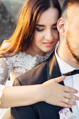 The lovely couple in love  embracing and sitting    on the stones