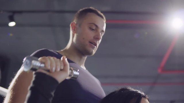A young woman is engaged in a gym with a personal trainer. 4K