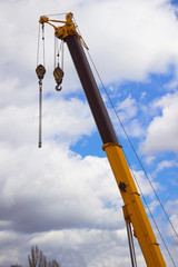 The boom of construction crane with the hook. Cloudy sky background